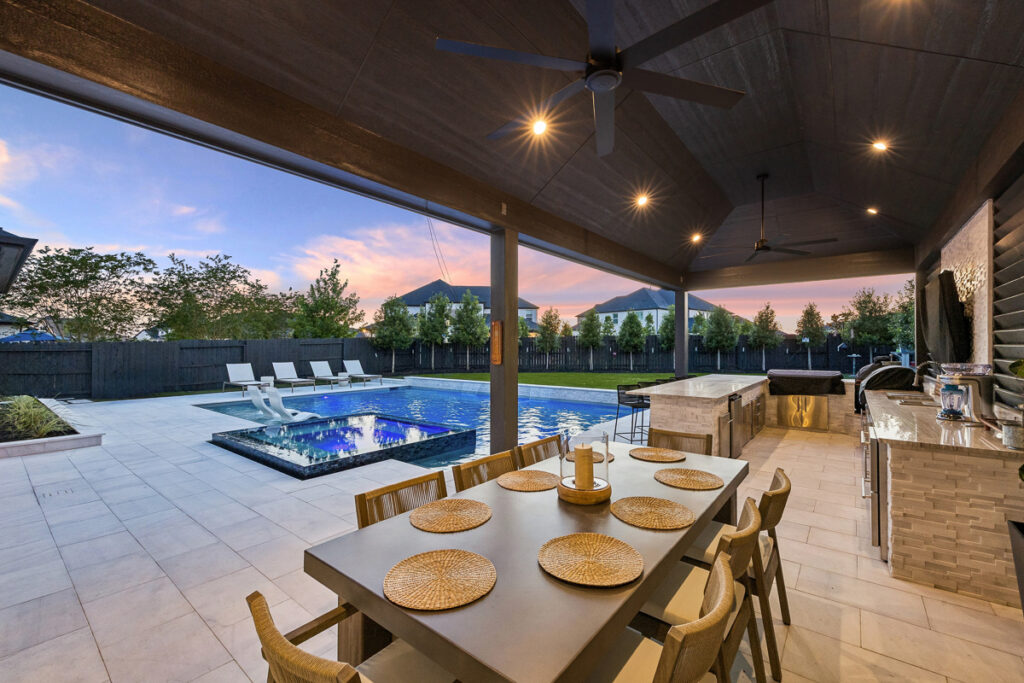 Covered patio with outdoor kitchen overlooking a custom pool